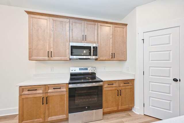 kitchen with light wood-type flooring, light countertops, and appliances with stainless steel finishes