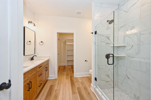 full bath featuring a marble finish shower, wood finished floors, and a sink