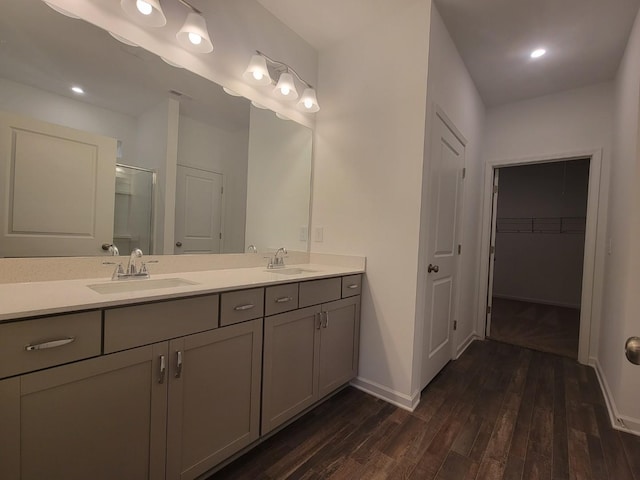 full bath with a sink, double vanity, a stall shower, and wood finished floors