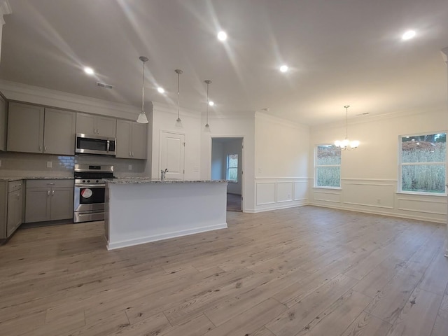 kitchen with gray cabinets, light stone counters, crown molding, an inviting chandelier, and appliances with stainless steel finishes