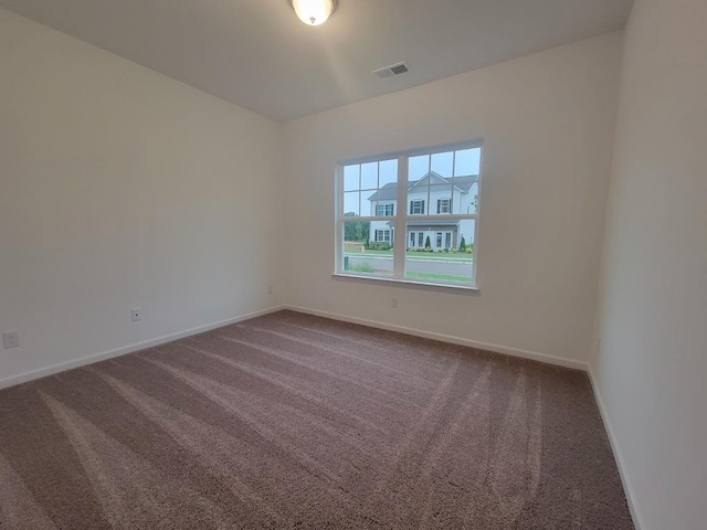 unfurnished room featuring baseboards, dark colored carpet, and visible vents