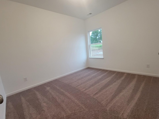 empty room with carpet flooring, visible vents, and baseboards