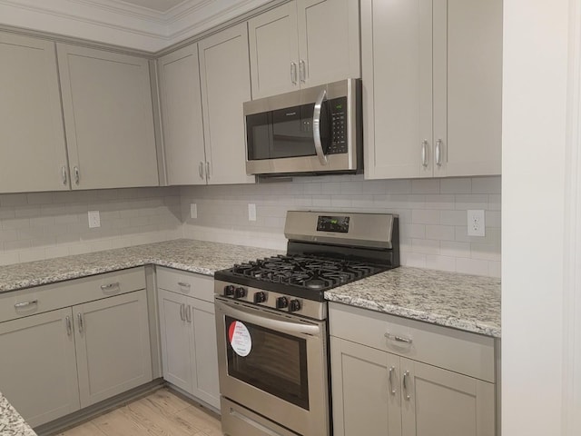 kitchen featuring backsplash, light stone counters, appliances with stainless steel finishes, and gray cabinets