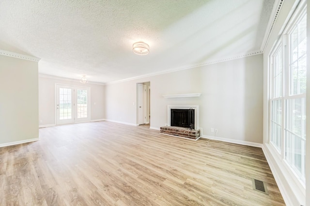 unfurnished living room featuring a fireplace, ornamental molding, visible vents, and light wood-style floors
