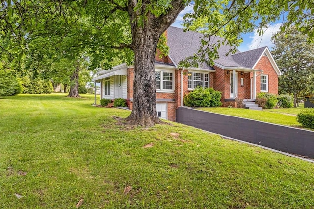 single story home with a shingled roof, brick siding, and a front yard