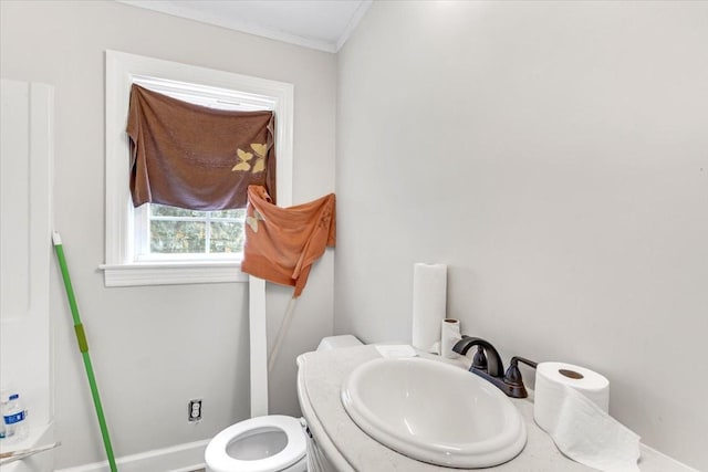 bathroom featuring a sink, ornamental molding, baseboards, and toilet