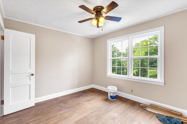 empty room featuring crown molding, wood finished floors, baseboards, and ceiling fan