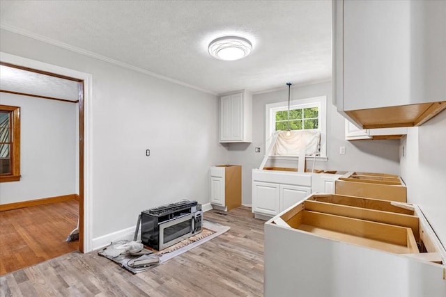 kitchen with light wood finished floors, white cabinets, and ornamental molding