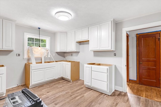 clothes washing area featuring light wood finished floors, crown molding, and baseboards
