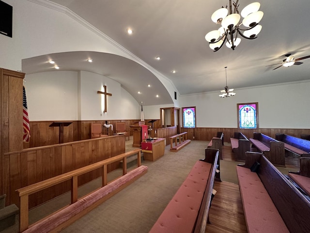 playroom featuring ceiling fan with notable chandelier, ornamental molding, vaulted ceiling, wooden walls, and wainscoting