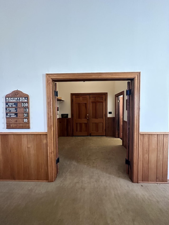 hallway with wood walls, wainscoting, and carpet floors