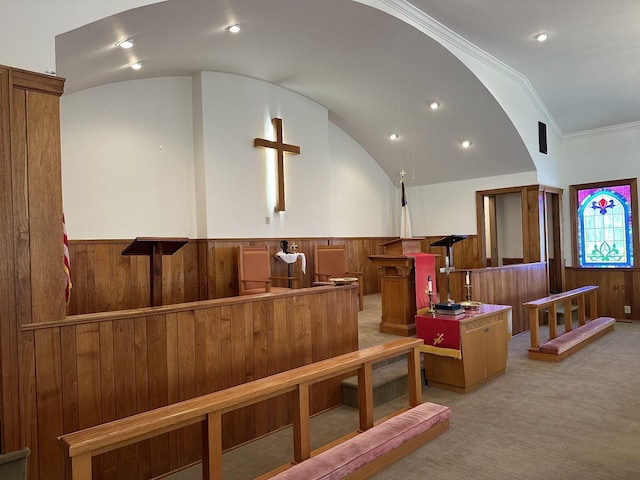 interior space with wood walls, crown molding, a wainscoted wall, vaulted ceiling, and light colored carpet