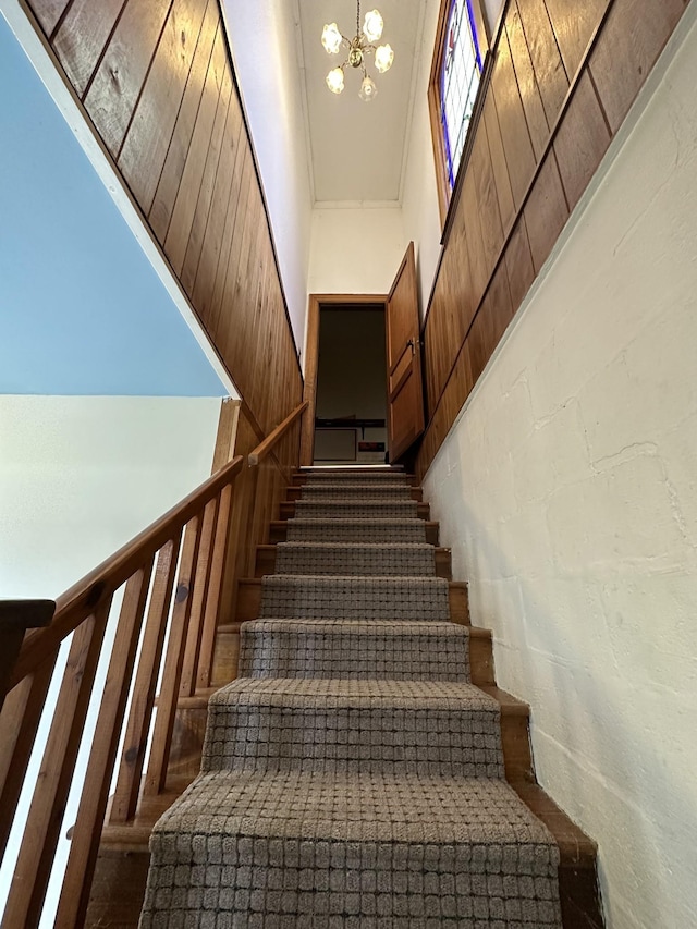stairway with ornamental molding and a notable chandelier