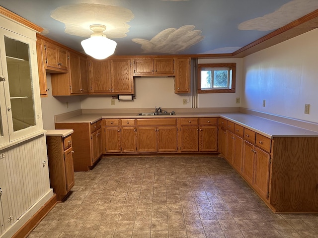 kitchen with a sink, light countertops, and brown cabinets