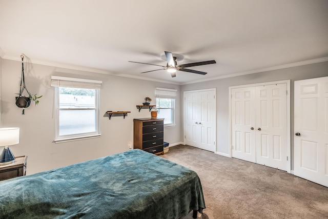 bedroom featuring two closets, carpet floors, crown molding, baseboards, and a ceiling fan