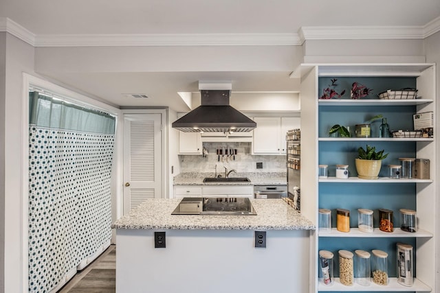 kitchen with black electric stovetop, wall chimney range hood, a sink, white cabinets, and wood finished floors