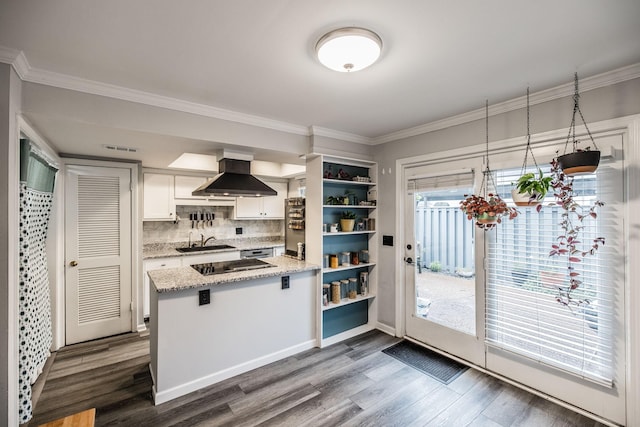 kitchen featuring island range hood, a peninsula, a sink, dark wood-style floors, and crown molding