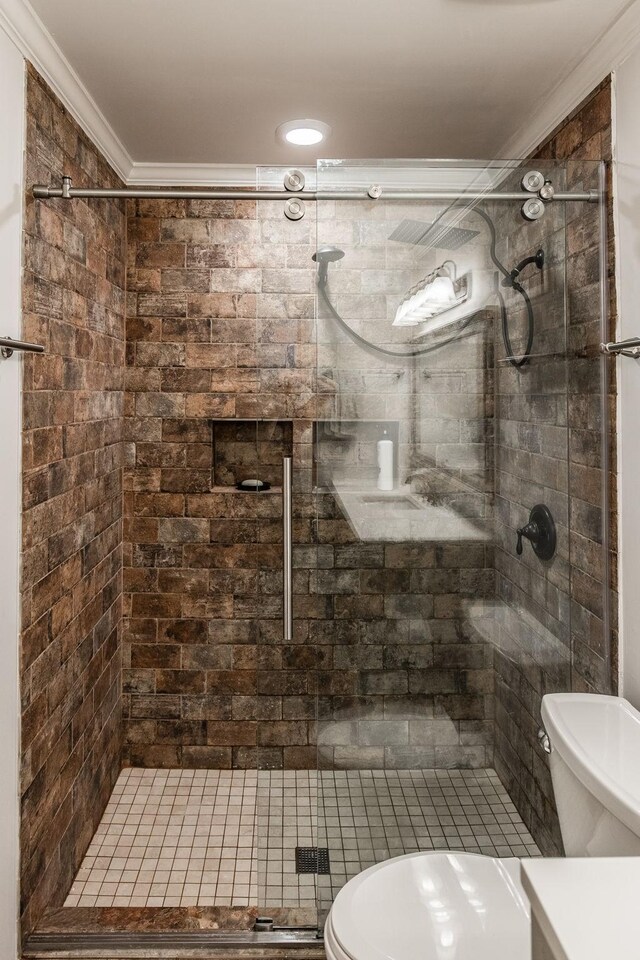 bathroom featuring toilet, ornamental molding, and a stall shower