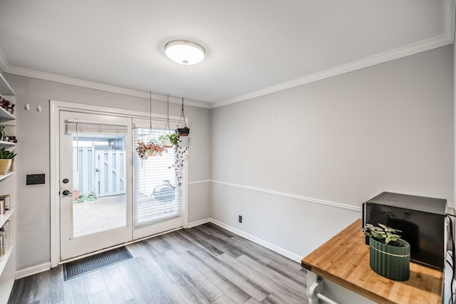 unfurnished dining area with wood finished floors, ornamental molding, and baseboards