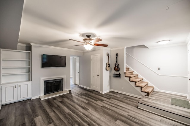 unfurnished living room with a ceiling fan, dark wood-type flooring, stairway, a fireplace with raised hearth, and baseboards