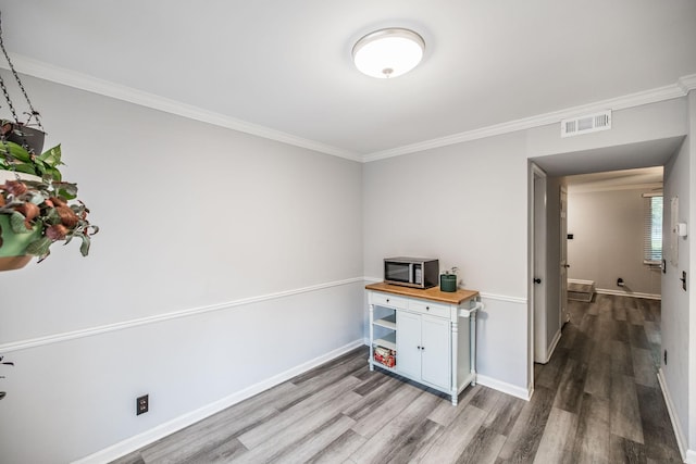 interior space featuring wood finished floors, baseboards, and ornamental molding