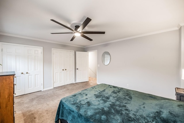 carpeted bedroom with ornamental molding, multiple closets, a ceiling fan, and baseboards