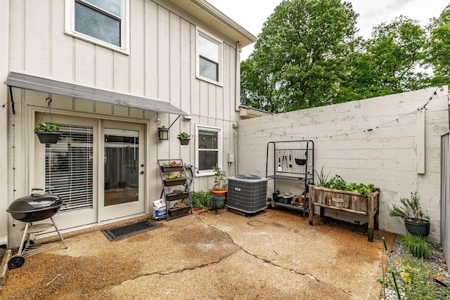back of property with board and batten siding, central air condition unit, a patio area, and a fenced backyard