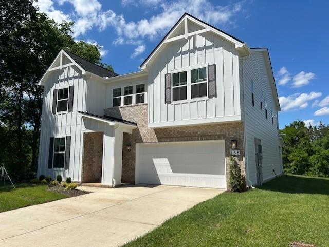 modern farmhouse style home with a front lawn, board and batten siding, and an attached garage