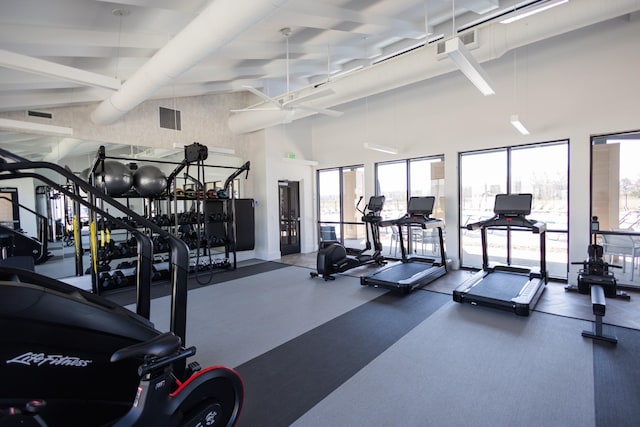 workout area with a ceiling fan, visible vents, and a high ceiling