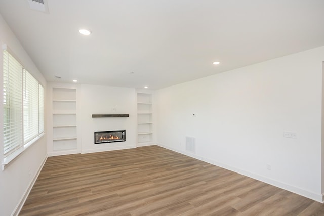 136 W Cassa Way, Mount Juliet, TN 37122 - unfurnished living room featuring baseboards, built in features, light wood-style floors, recessed lighting, and a glass covered fireplace