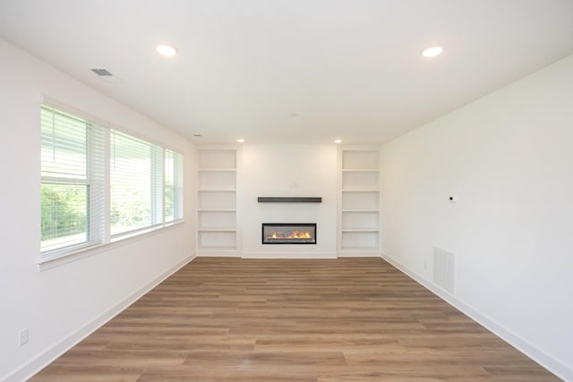 unfurnished living room with baseboards, recessed lighting, a glass covered fireplace, and visible vents