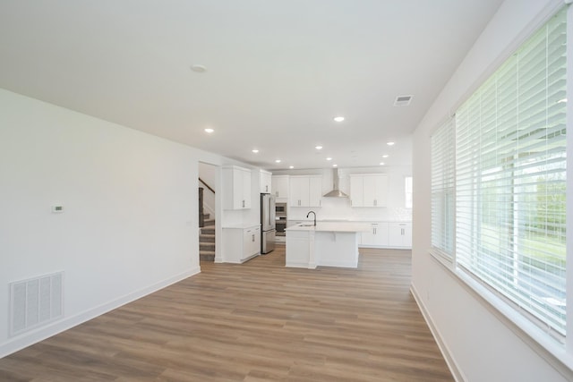 unfurnished living room featuring a sink, light wood finished floors, visible vents, and stairway