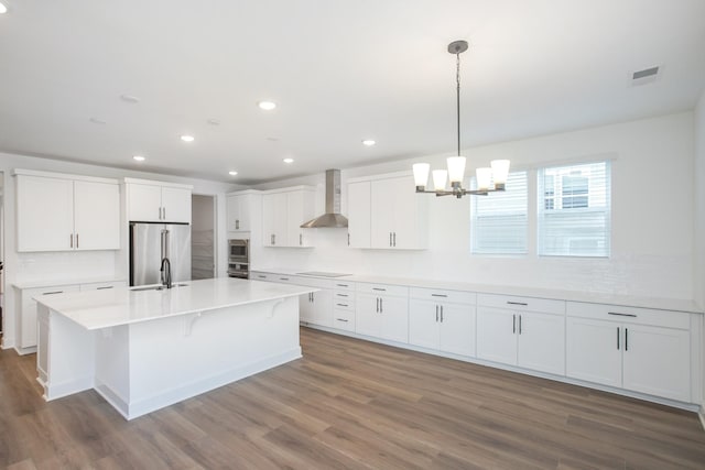 kitchen with high quality fridge, a sink, wood finished floors, wall chimney range hood, and white cabinets