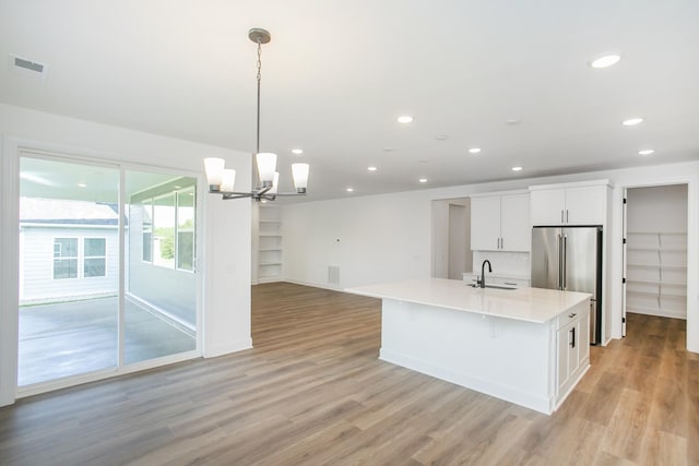 kitchen featuring light countertops, visible vents, light wood-style flooring, and a sink