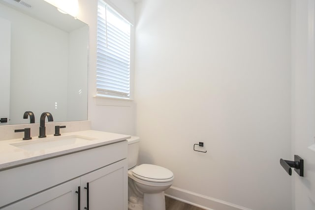 bathroom featuring toilet, wood finished floors, vanity, and a healthy amount of sunlight
