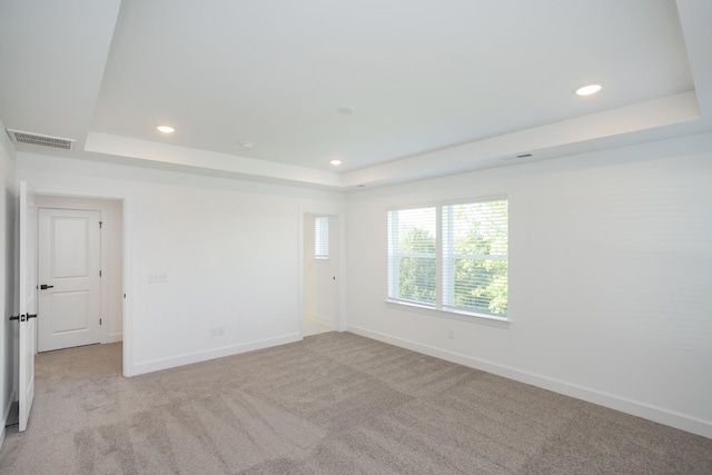 unfurnished room with visible vents, baseboards, a raised ceiling, and light carpet