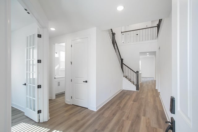 hallway with recessed lighting, light wood-style floors, baseboards, and stairs