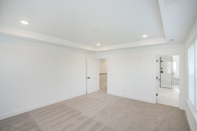 empty room with a tray ceiling, light colored carpet, and recessed lighting