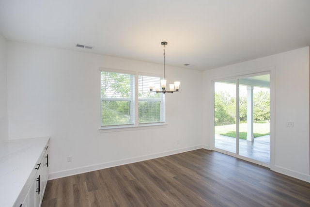 unfurnished dining area with a notable chandelier, baseboards, visible vents, and dark wood finished floors