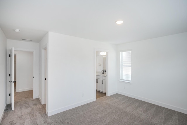 spare room with a sink, light carpet, and baseboards