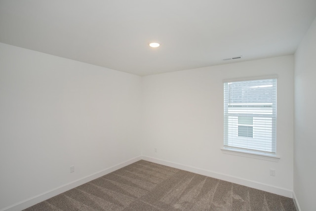 spare room with carpet floors, baseboards, a healthy amount of sunlight, and visible vents