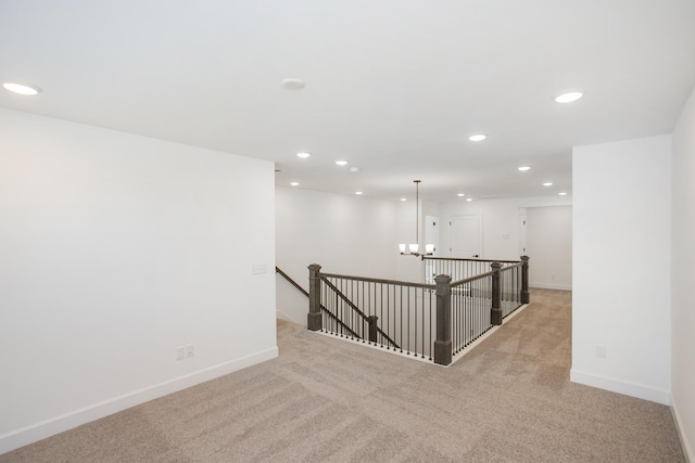 empty room featuring light colored carpet, baseboards, a chandelier, and recessed lighting