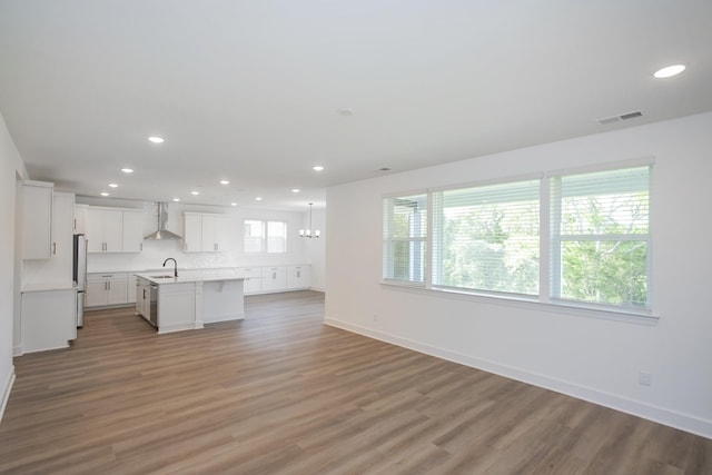 unfurnished living room featuring a sink, light wood-type flooring, visible vents, recessed lighting, and baseboards