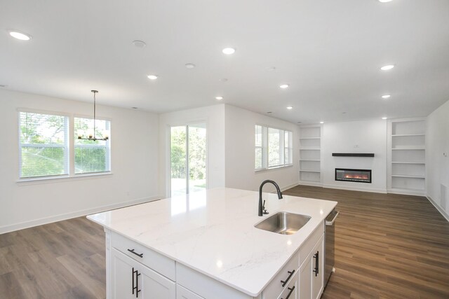 kitchen featuring dark wood finished floors, built in features, a sink, open floor plan, and white cabinets