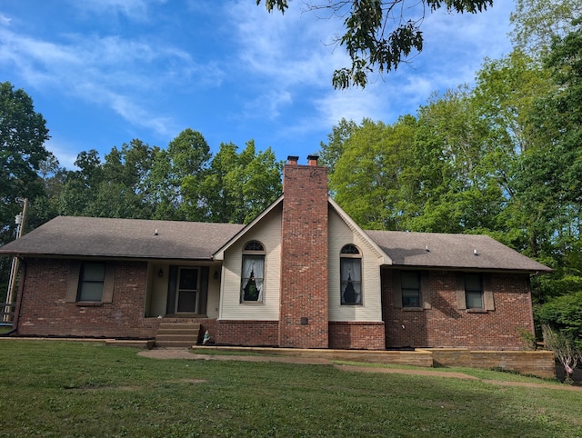 ranch-style home with a chimney, roof with shingles, brick siding, and a front lawn
