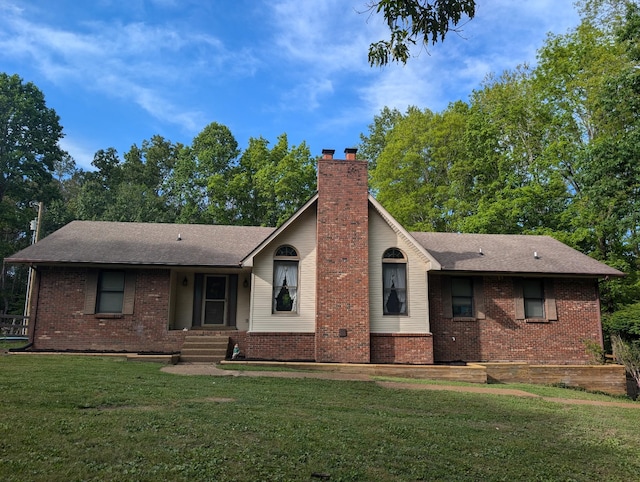 ranch-style home featuring roof with shingles, a chimney, brick siding, and a front yard