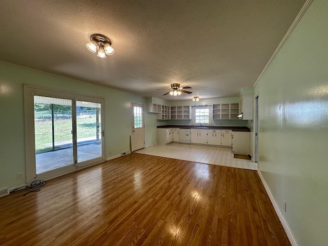 unfurnished living room with baseboards, a ceiling fan, a textured ceiling, and wood finished floors