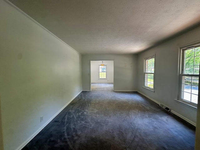 empty room featuring a textured ceiling, dark colored carpet, baseboards, and visible vents