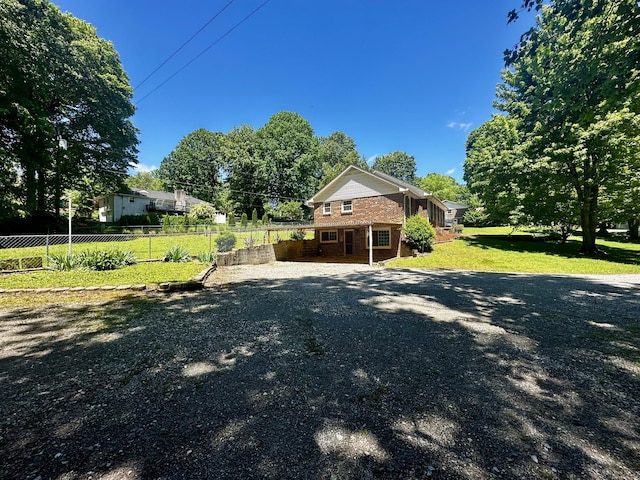 view of front facade with a front lawn, brick siding, and fence