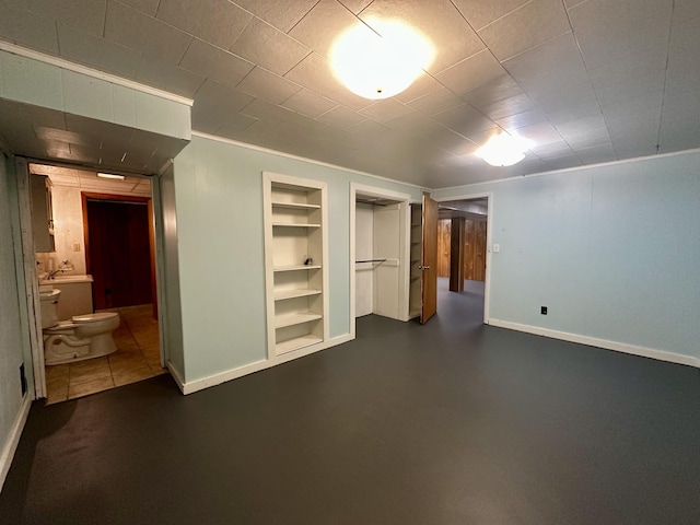 finished below grade area featuring built in shelves and baseboards